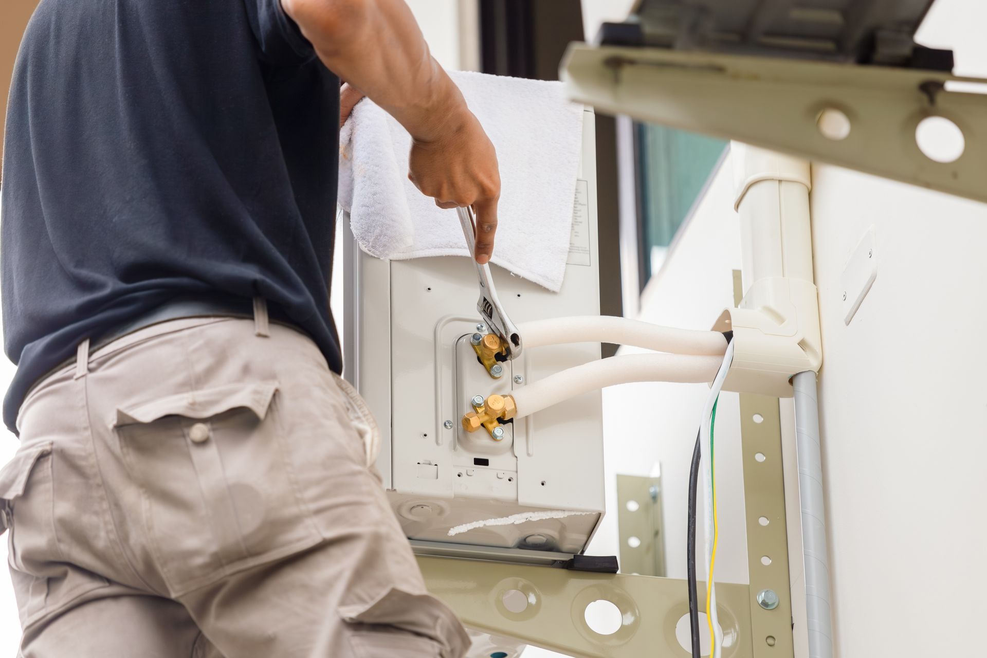 Technician using a wrench to install an air conditioning system during]