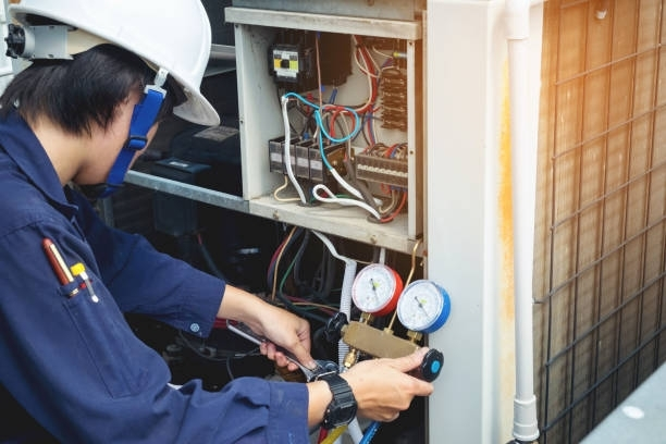 HVAC technician checking refrigerant pressure gauges on commercial air conditioning unit