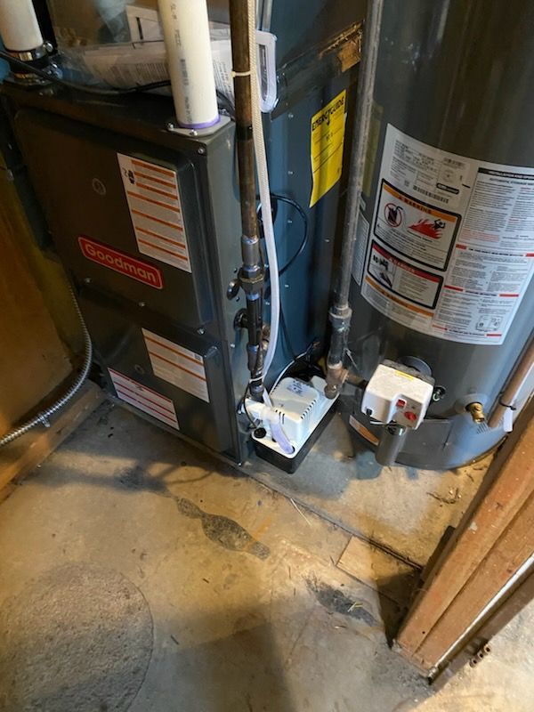 Heating Installation and Repair Basement utility room with a furnace and water heater beside a floor drain and exposed pipes