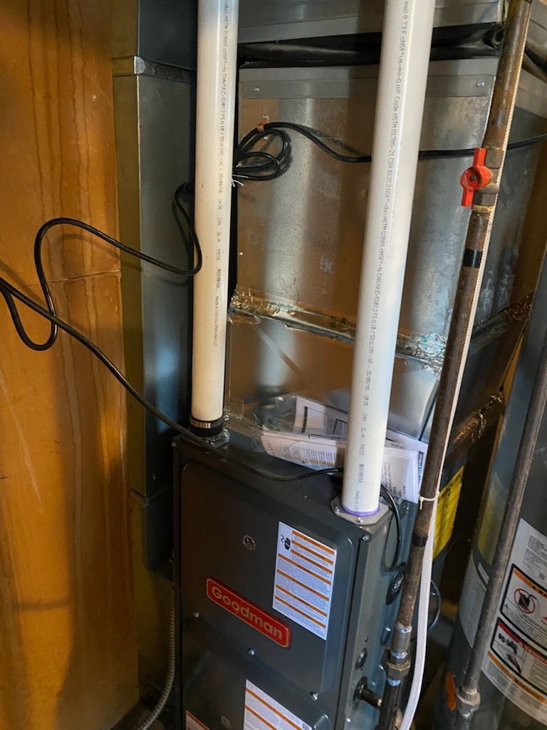 Pressure gauges on HVAC unit, showcasing professional furnace repair services. Furnace with white PVC pipes and wiring in a basement utility area