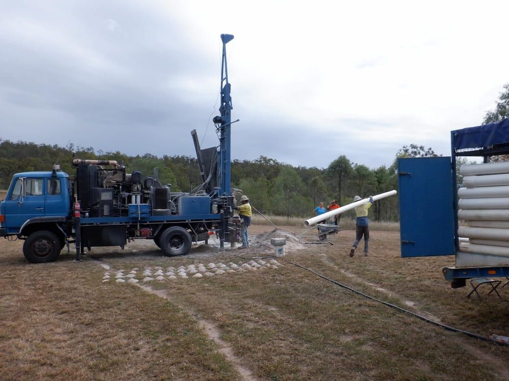 A Blue Truck is Parked in a Field Next to a Stack of Pipes — Cheyenne Drilling on the Sunshine Coast, QLD