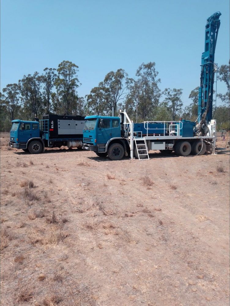A Blue Truck is Parked Next to a White Truck in a Field — Cheyenne Drilling on the Sunshine Coast, QLD
