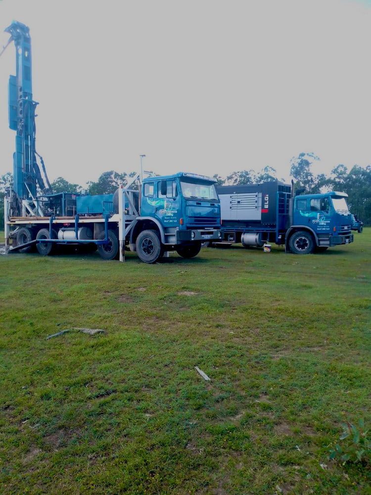 Two Blue Trucks Are Parked in a Grassy Field — Cheyenne Drilling on the Sunshine Coast, QLD