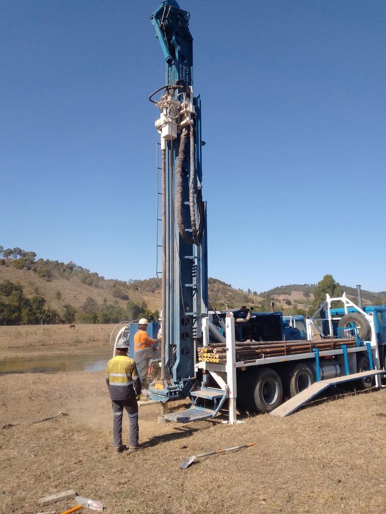A Man Standing Next to a Large Machine in a Field — Cheyenne Drilling on the Sunshine Coast, QLD
