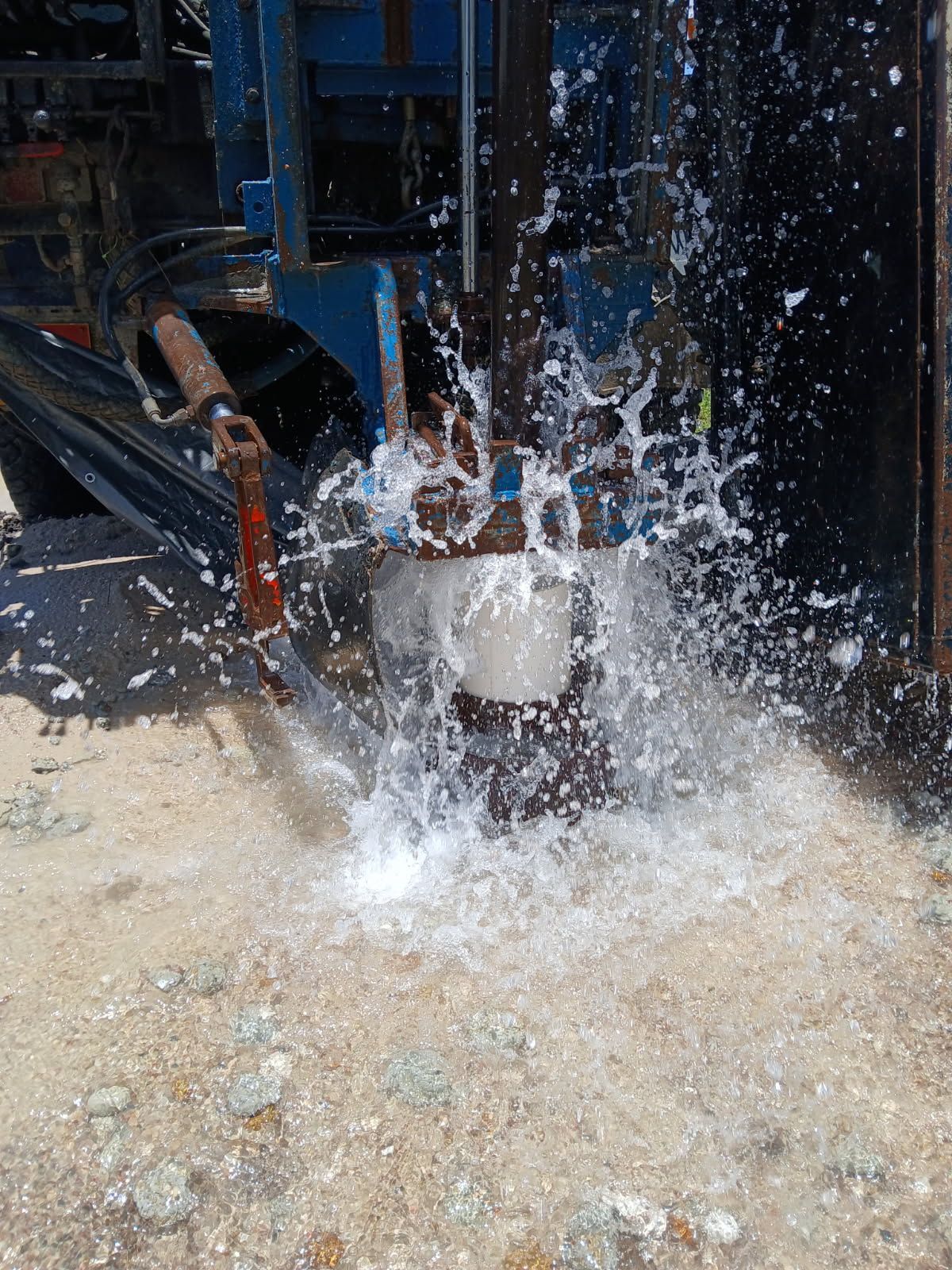 Water gushing from well drilling machinery, spraying onto a gravel surface — Cheyenne Drilling on the Sunshine Coast, QLD