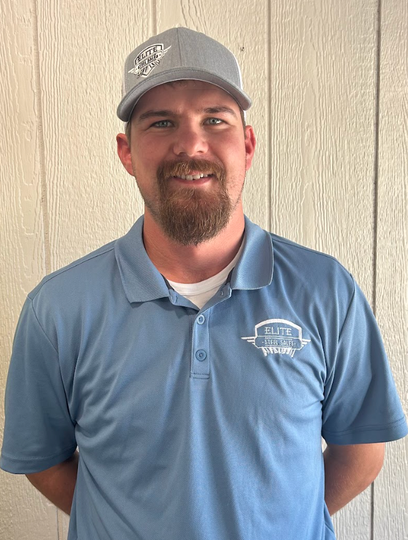 Man wearing a blue polo shirt and gray hat with logo, smiling.
