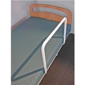 A bed with a white railing on the side of it