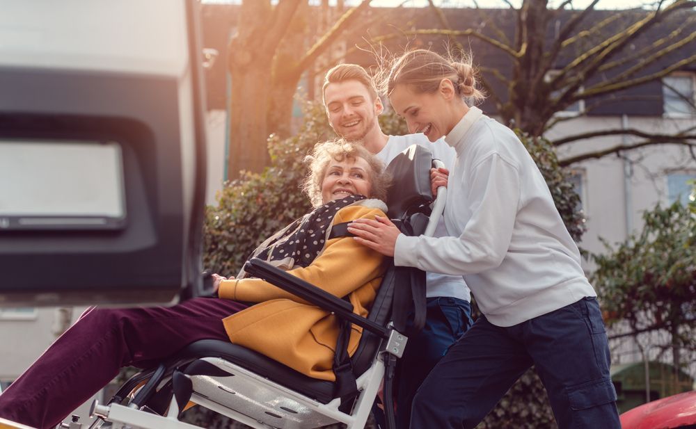 Family Helping Elderly Into Adaptive Car Seat Outdoors