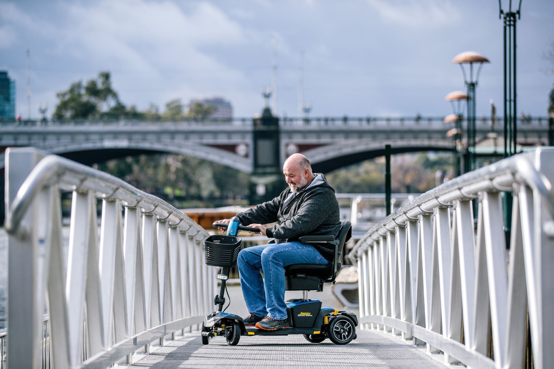 Man Riding Mobility Scooter On Footbridge Near Waterway on the Central Coast
