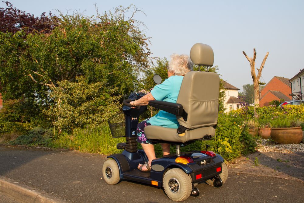 Woman On A Mobility Scooter Driving On Pavement 
