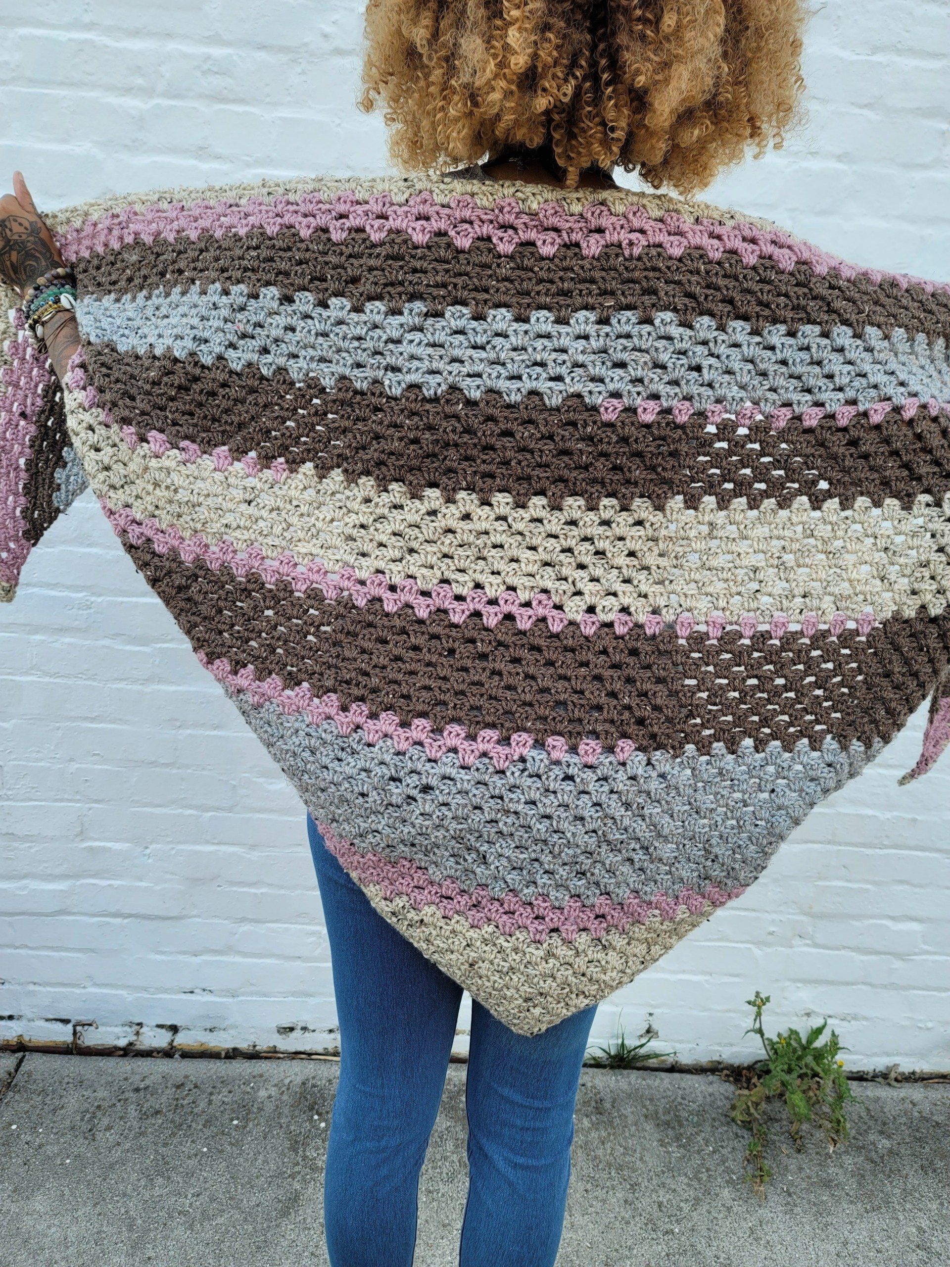 A woman is wearing a striped shawl over her shoulders.