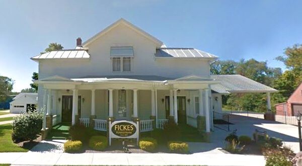 White house with porch and sign reading “PICKERS” under a bright blue sky