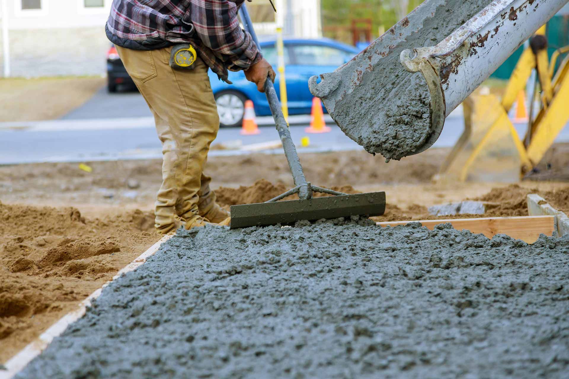A man is raking concrete on a construction site