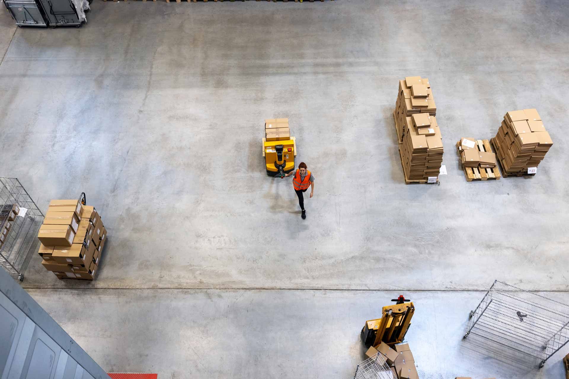 An aerial view of a warehouse with a man standing in the middle of it