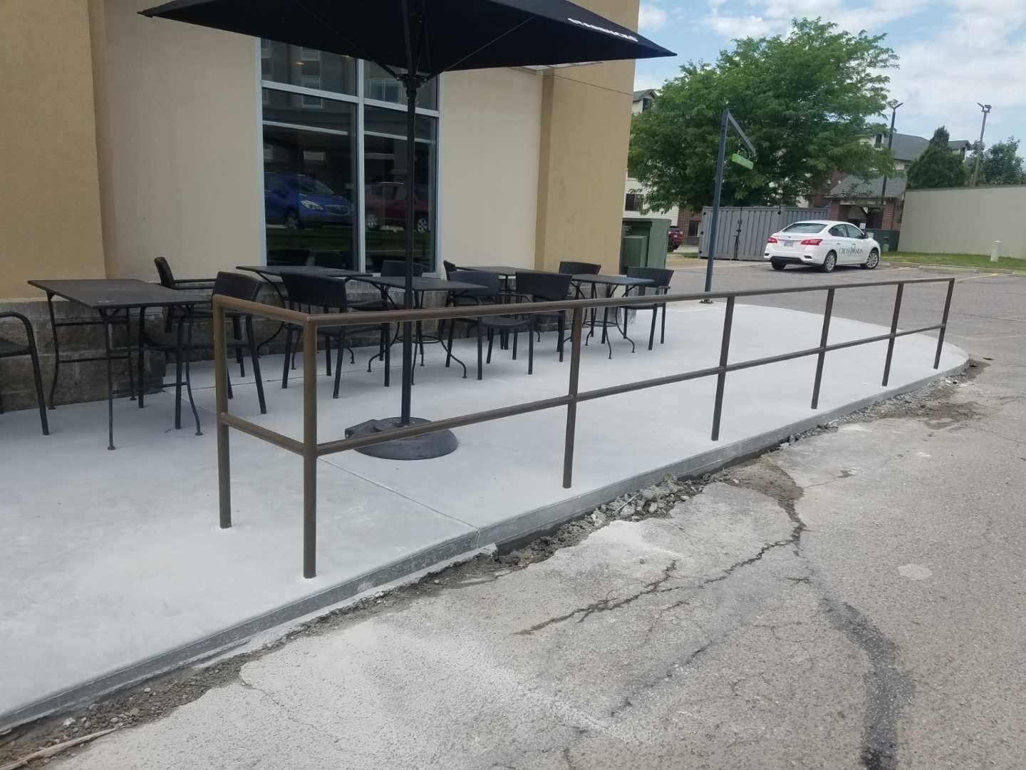 A patio with tables and chairs and an umbrella in front of a building