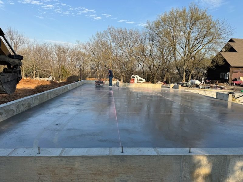 Concrete slab foundation being smoothed with a power trowel on a construction site outdoors