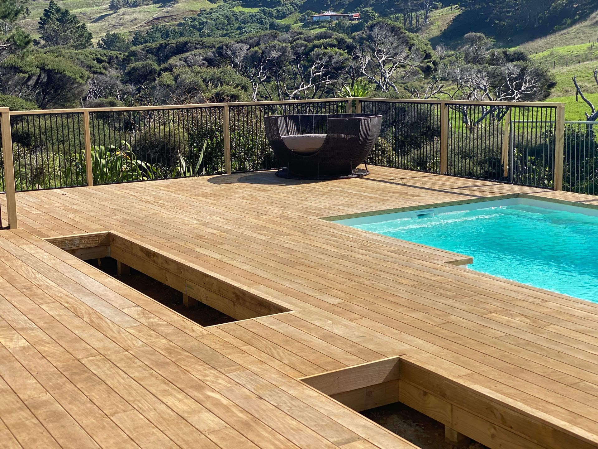 Wooden deck with built-in pool overlooking green hills and mountains