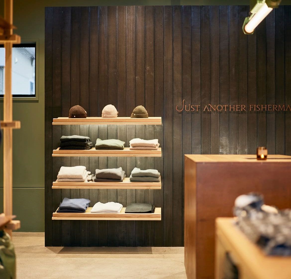 Interior of a minimalist clothing store with folded sweaters on shelves and dark wood walls