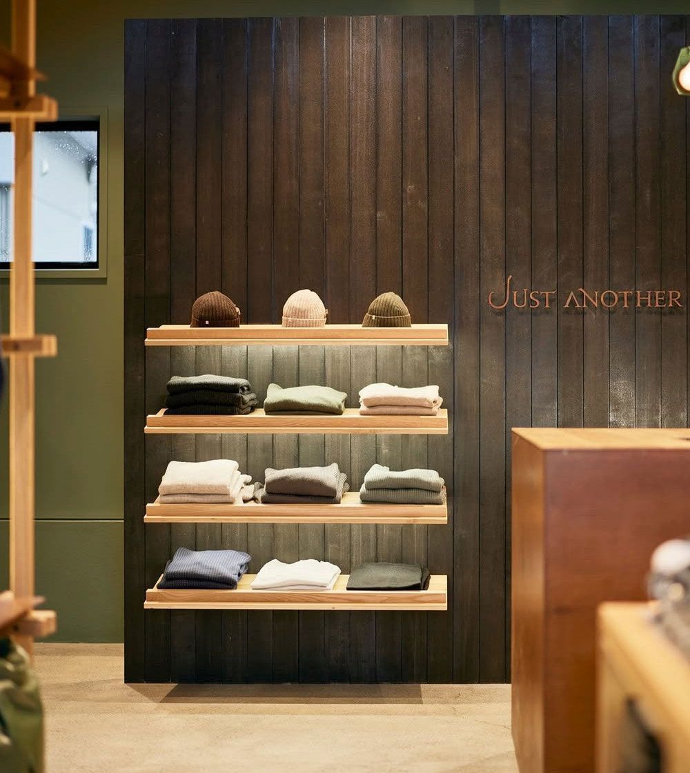 Wood-paneled boutique shelf with neatly folded clothes and hats under warm lighting