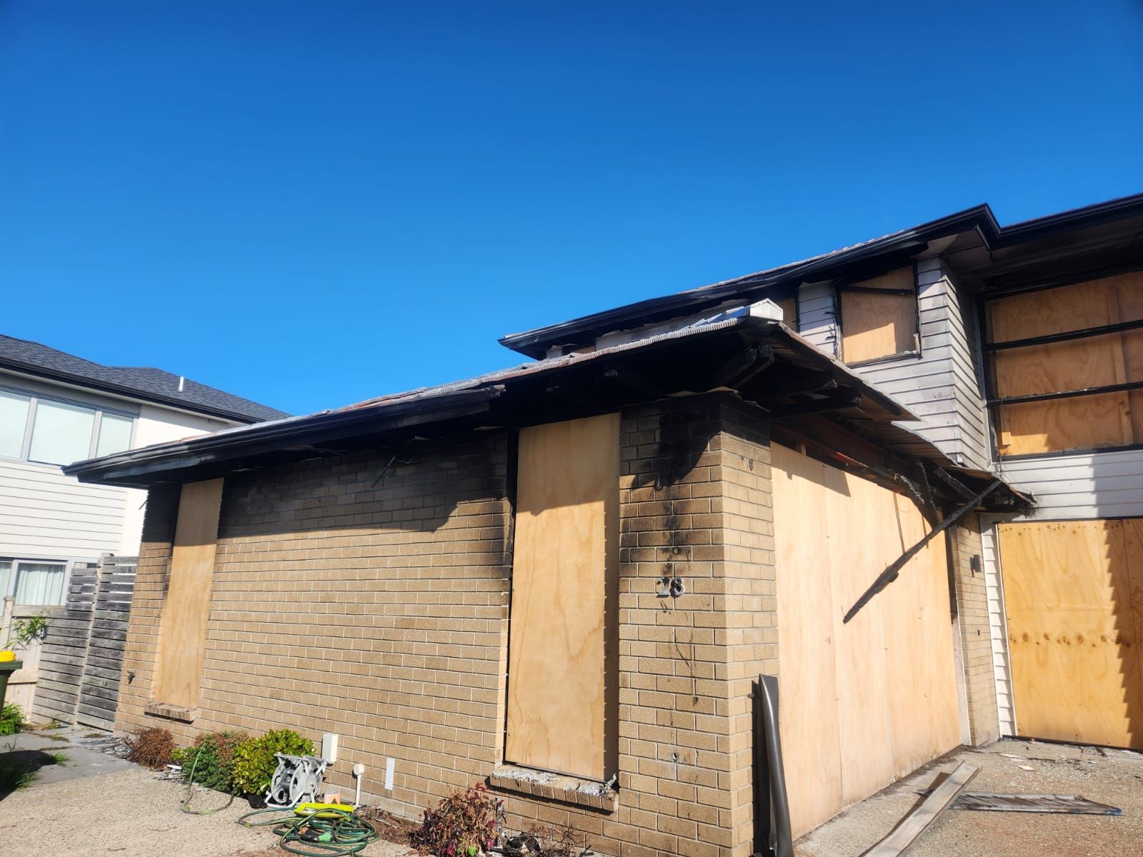 Old wooden shed with boarded windows and a slanted roof in a sunny yard.