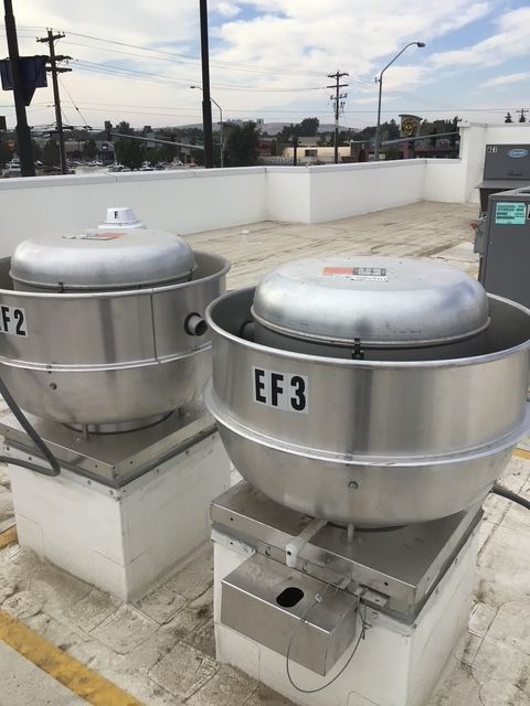 Two rooftop metal exhaust fans labeled EF2 and EF3 on a white concrete platform.