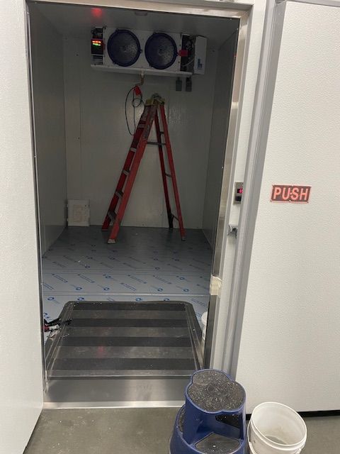 Open utility closet with red ladder, buckets on floor, and a wet room inside; door marked “PUSH”