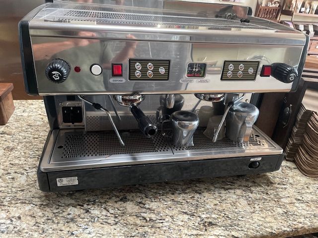 Stainless steel espresso machine with multiple group heads and portafilters on a countertop