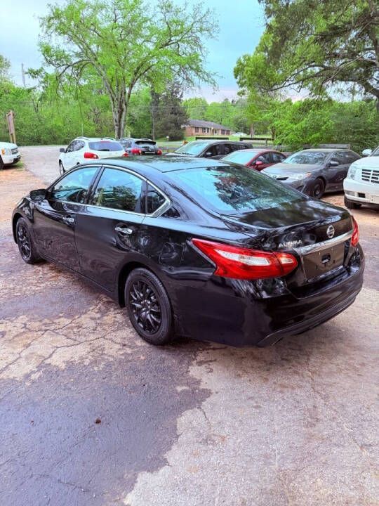 Black sedan parked on a tree-lined lot with several cars in the background