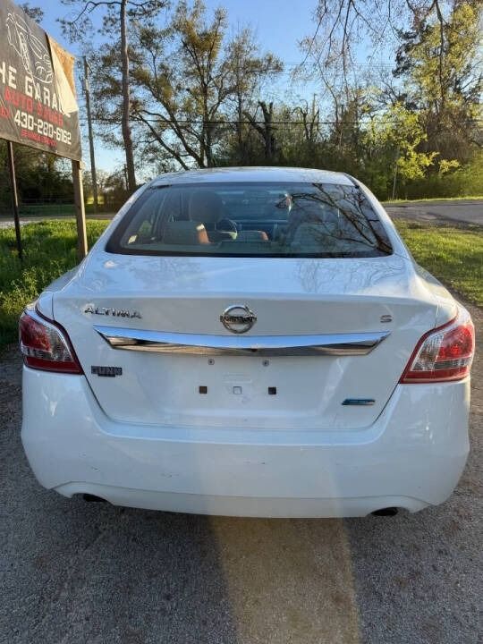 Rear view of a white Nissan sedan parked on a roadside, with trees and a sign in the background.