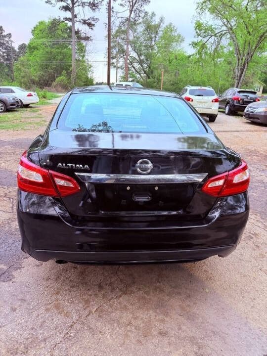 Black Nissan Altima sedan parked outdoors in a lot, rear view.