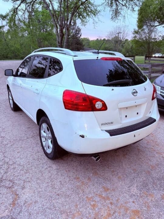 White SUV parked on a gravel roadside with trees in the background.