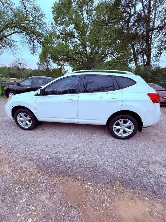 White SUV parked on a gravel lot with trees and another car in the background.