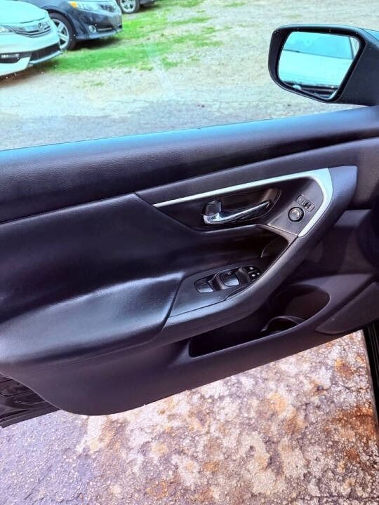 Car door interior with black trim, handle, window controls, and side mirror visible