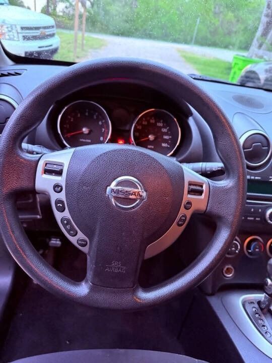 Nissan steering wheel and dashboard viewed from the driver’s seat, with parked cars visible through the windshield