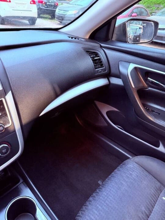 Car interior with black dashboard, silver trim, passenger seat, cup holder, and side mirror view outside