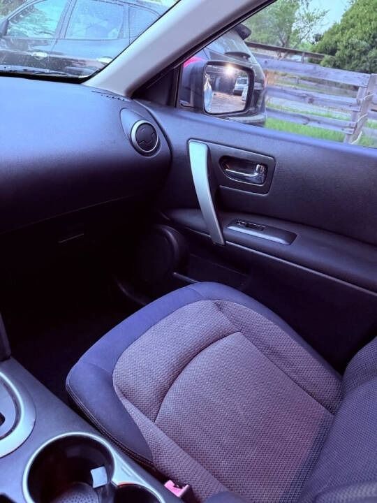 Car interior with gray passenger seat, door panel, side mirror, and a glimpse of a fence outside the window