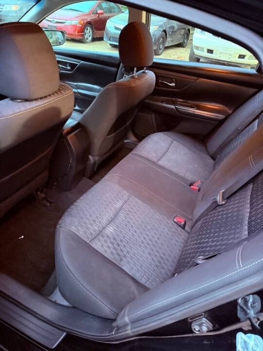 Car interior with gray cloth back seat, black front seats, and a red car visible outside the window