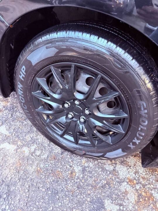 Close-up of a black car wheel with a shiny tire on a wet pavement.