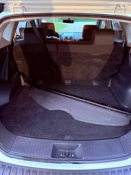 Open car trunk with cargo cover and folded rear seats, showing a spacious empty cargo area.