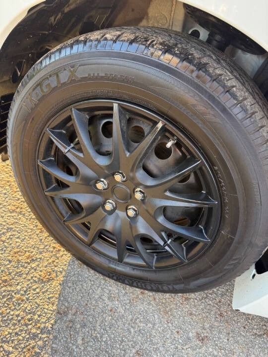 Black car wheel with alloy rim and low tire, parked on pavement