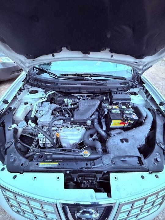 Open car hood showing engine bay and battery in a light blue sedan