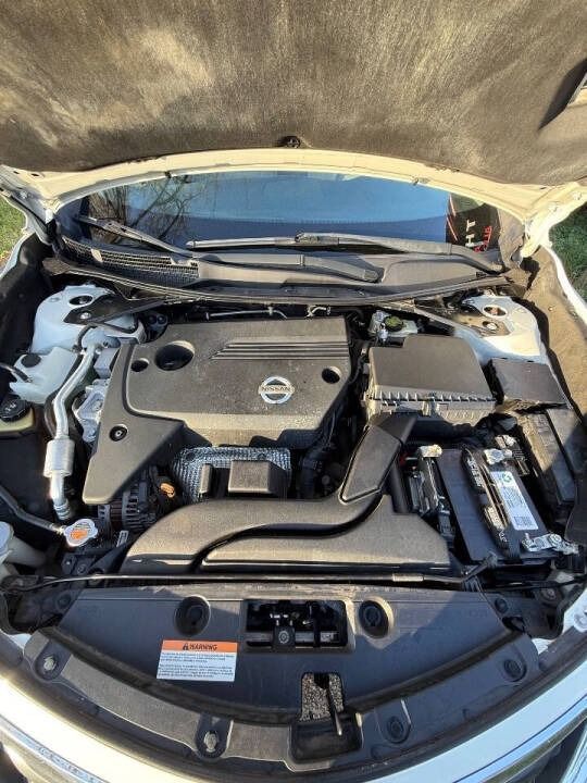 Open Nissan car engine bay with black engine cover and exposed battery