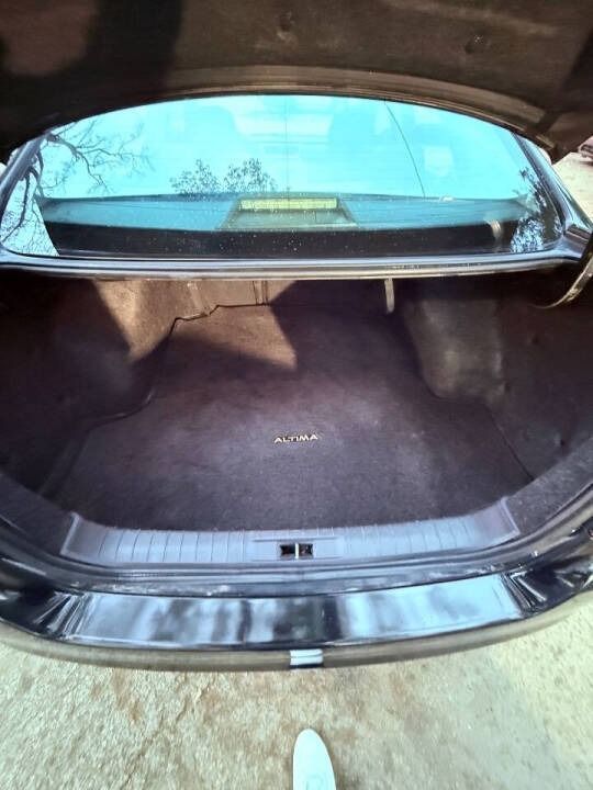 Open car trunk with dark carpeted cargo area and rear window visible above.