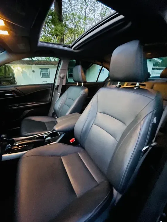 Black leather car interior with sunroof, front seats, and center console
