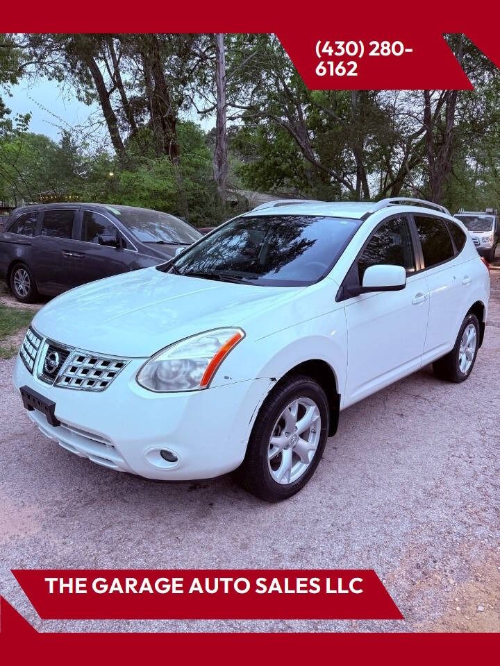 White Nissan SUV for sale parked outdoors at The Garage Auto Sales LLC, with phone number displayed.