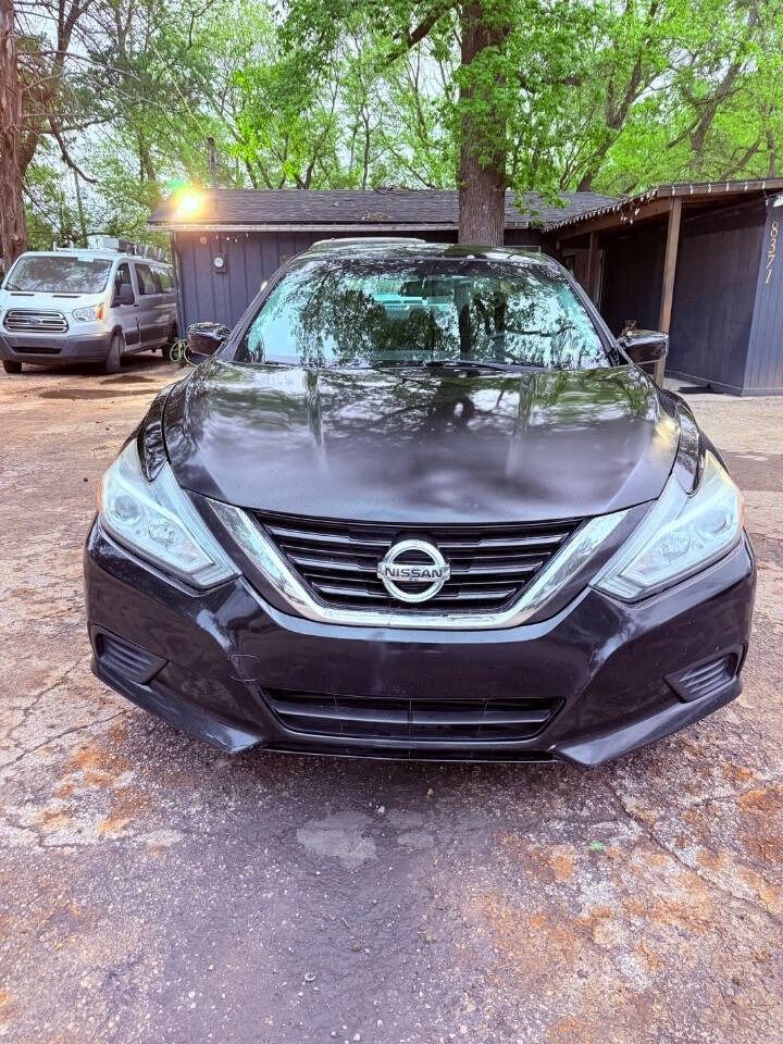 Black Nissan sedan parked in a driveway with trees and a house in the background