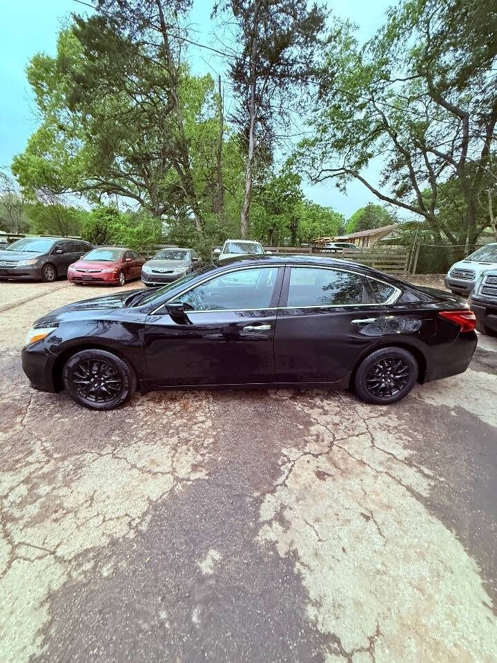 Black sedan parked in a lot with trees and other cars in the background