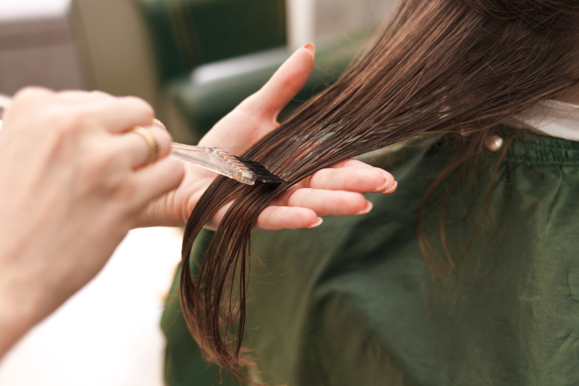 Hair being sectioned with a comb during a haircut, with long brown hair visible