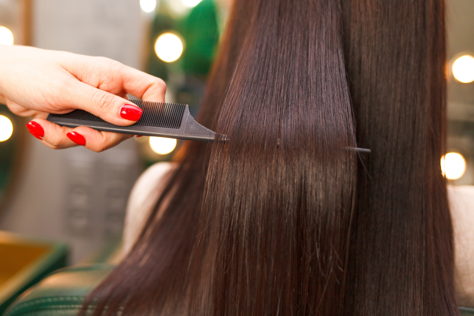 Hand combing long straight brown hair in a salon setting