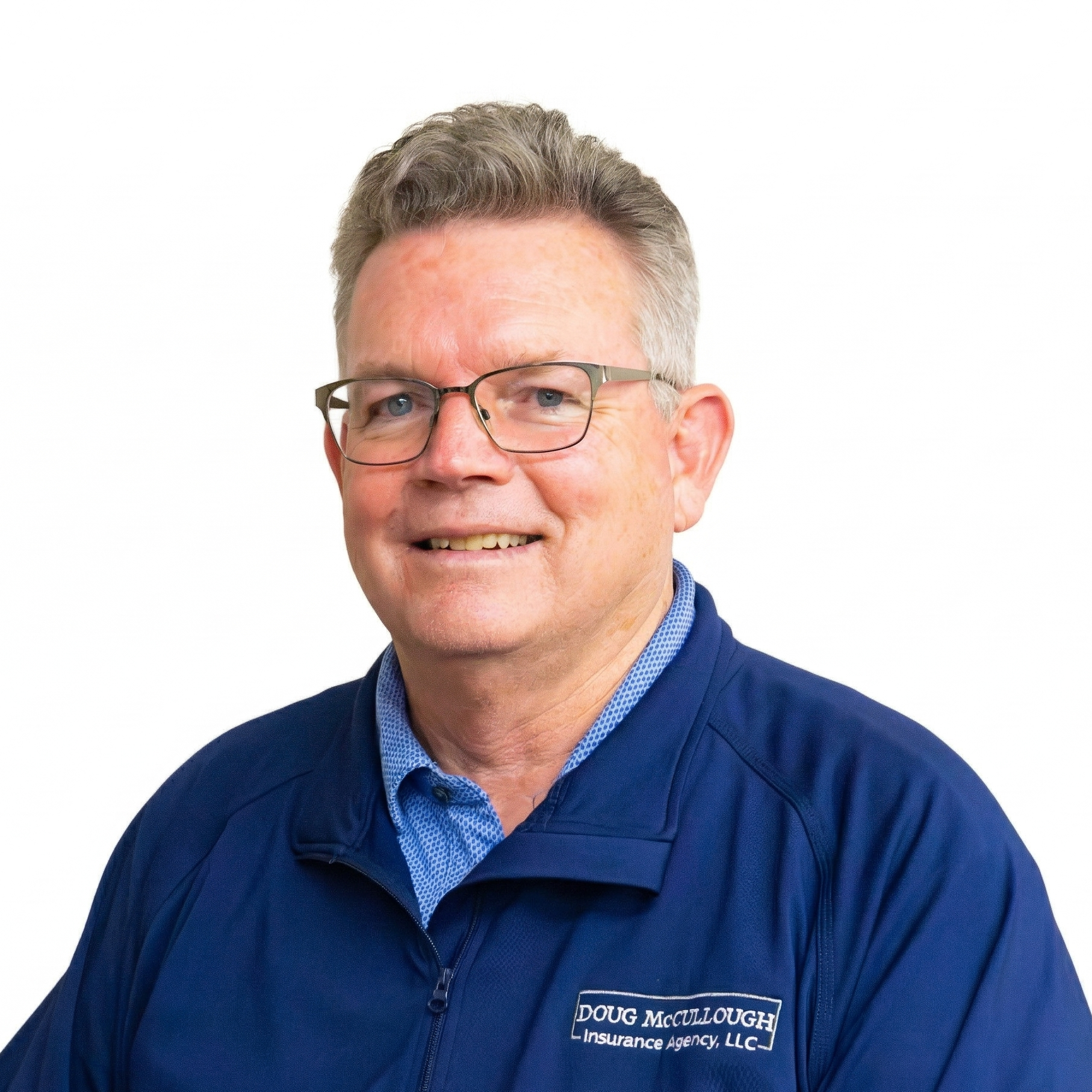 Portrait of a smiling man in glasses wearing a blue collared shirt and jacket on a white background